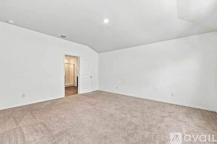 A spacious room with a carpeted floor and a doorway leading to another room.