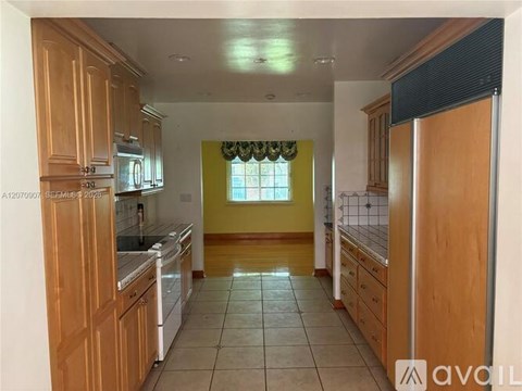 A kitchen with wooden cabinets and a tiled floor.