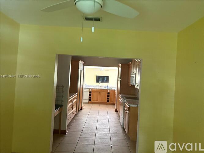 A kitchen with a tiled floor and a ceiling fan.