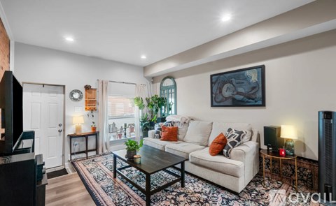 A living room with a white couch, a coffee table, and a painting on the wall.