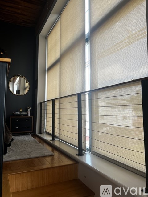 A room with a wooden floor and a large window with blinds.