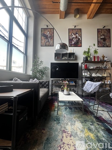 A living room with a black couch and a TV on a stand.