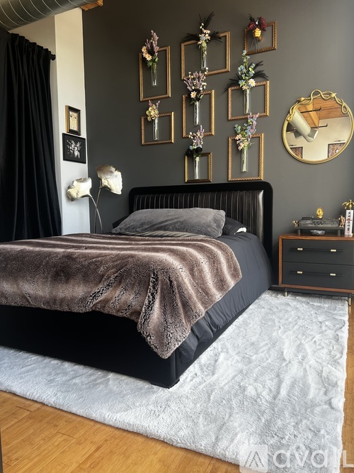 A bedroom with a black bed and a grey blanket.