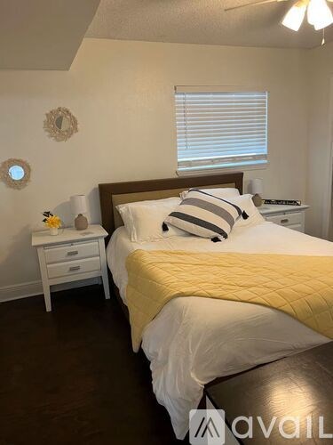 A bedroom with a bed, nightstand, and window.