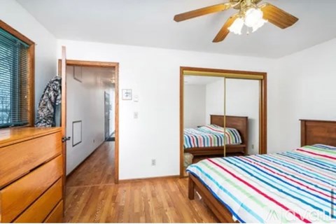 A bedroom with a bed, dresser, mirror and a ceiling fan.