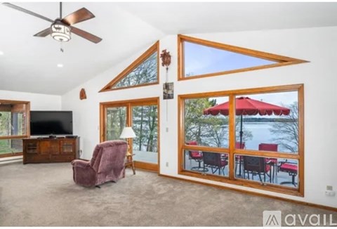 A living room with a red chair and a ceiling fan.