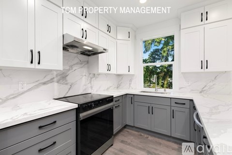 A kitchen with white cabinets and a marble countertop.