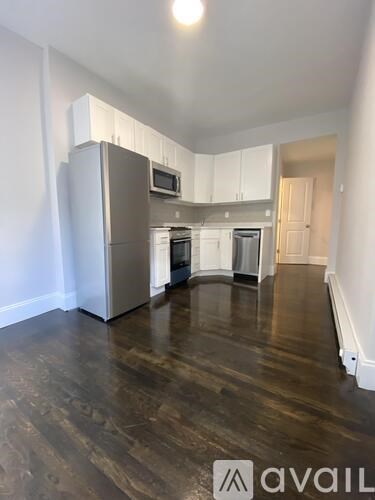 A kitchen with white cabinets and a wooden floor.