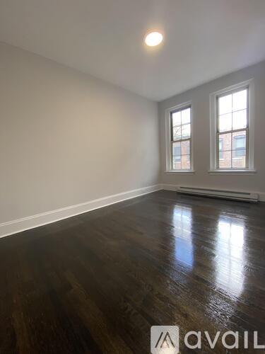 A room with wooden floors and two windows.