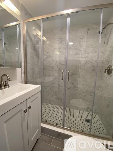 A white sink with a glass shower stall with a glass door.
