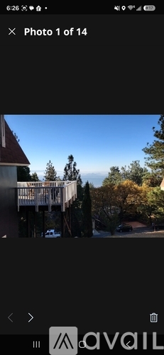 A building with a balcony overlooking a tree-lined street.