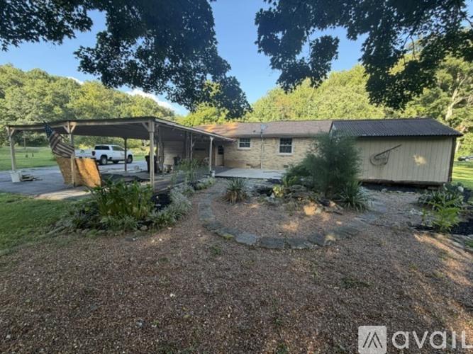A gravel area leads to a building with a covered porch.