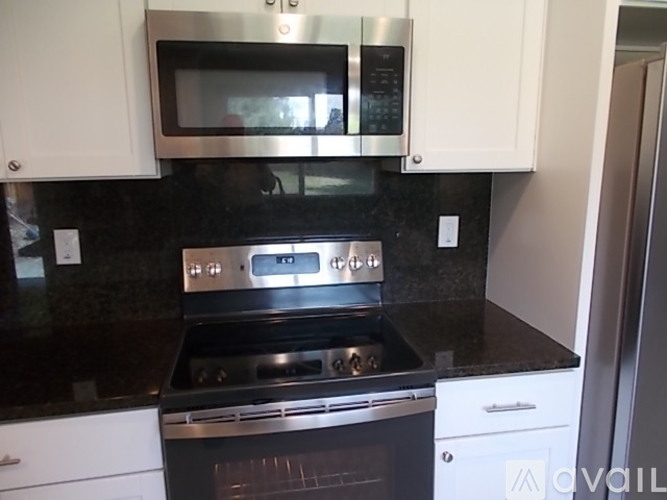 A kitchen with a black countertop and stainless steel appliances.