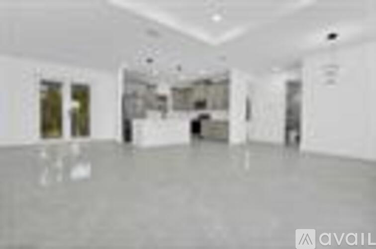 A spacious room with white walls and a reflective floor.