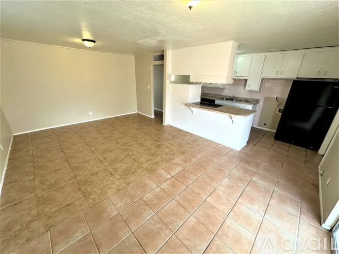 A kitchen area with a black refrigerator and white cabinets.