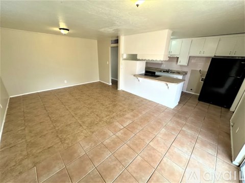 A kitchen area with a black refrigerator and white cabinets.