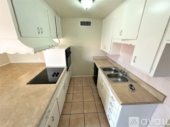 A kitchen with white cabinets and a black countertop.