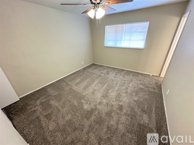 A room with a ceiling fan and carpeted floor.
