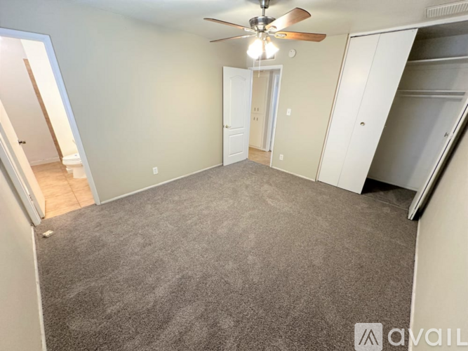 A spacious room with a ceiling fan and carpeted floor.
