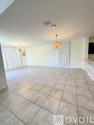A spacious room with tiled flooring and a hanging light fixture.