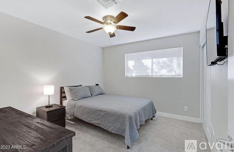A bedroom with a bed, a nightstand, and a ceiling fan.