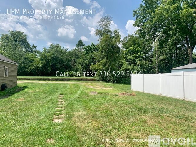 A grassy field with a white fence and trees in the background, with text overlay for HPM Property Management.