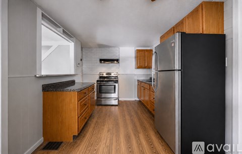 A kitchen with a black refrigerator and wooden cabinets.