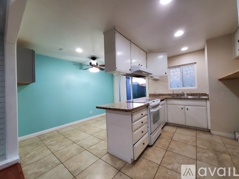 A kitchen with white cabinets and a tiled floor.