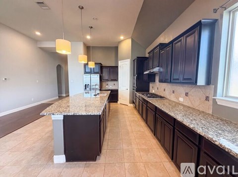 A kitchen with a granite countertop and dark brown cabinets.