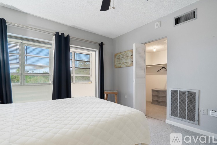A bedroom with a large bed and a window with curtains.