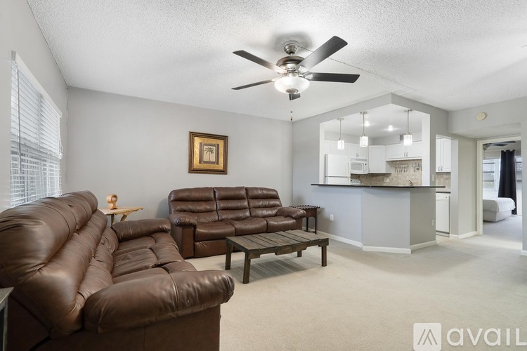 A living room with a brown leather couch and a ceiling fan.