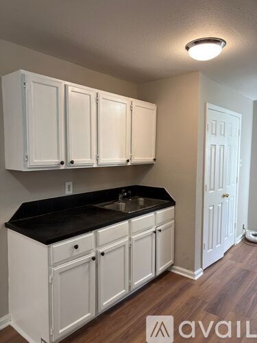 A kitchen with white cabinets and a black countertop.