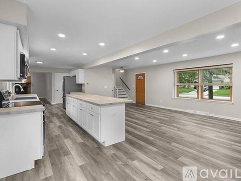 A spacious kitchen with white cabinets and a wooden floor.