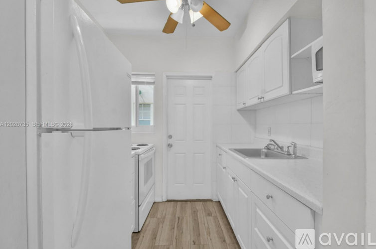 A kitchen with white appliances and cabinets.