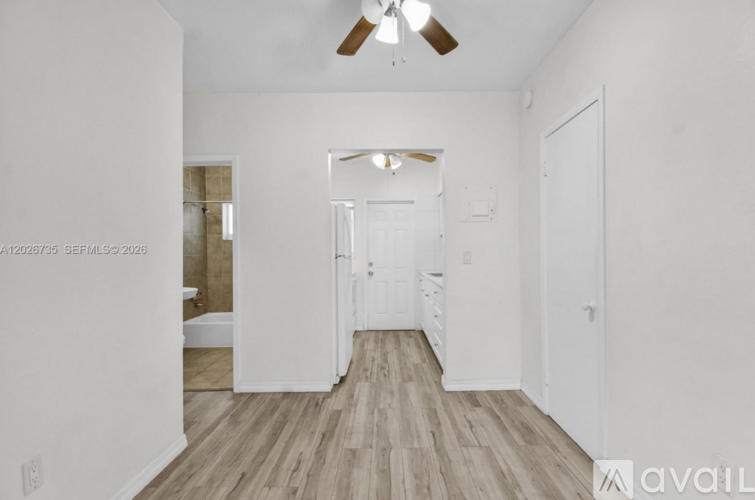 A spacious room with a ceiling fan and wooden flooring.