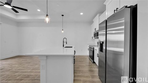 A modern kitchen with a stainless steel refrigerator and a wooden floor.