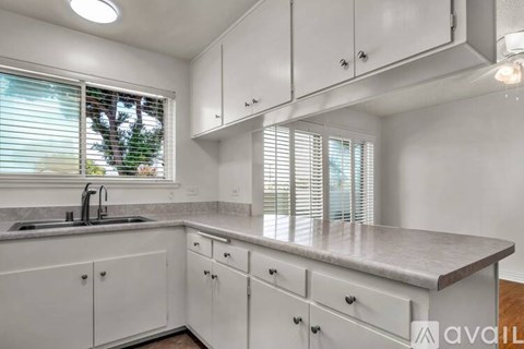 A kitchen with white cabinets and a marble countertop.