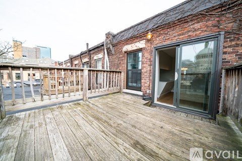 A wooden deck with a brick building and a glass door.