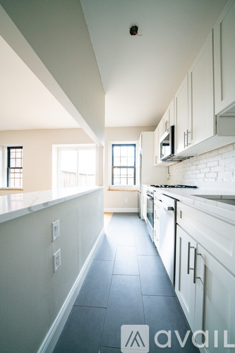A kitchen with white cabinets and a tiled floor.