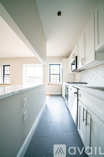 A kitchen with white cabinets and a tiled floor.
