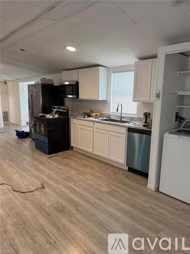 A kitchen with wooden floors and white cabinets is shown.