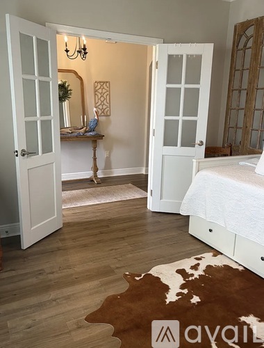 A white bedroom with a cowhide rug and a chandelier.