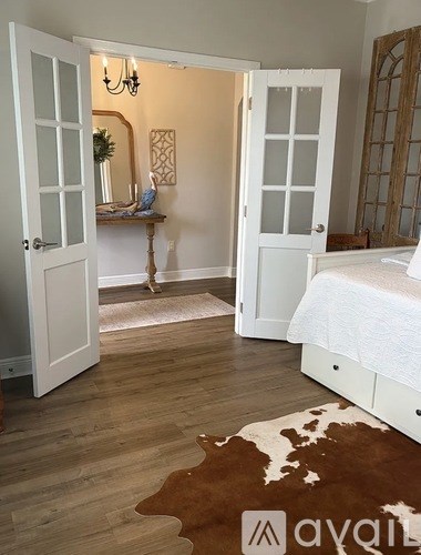 A white bedroom with a cowhide rug and a chandelier.