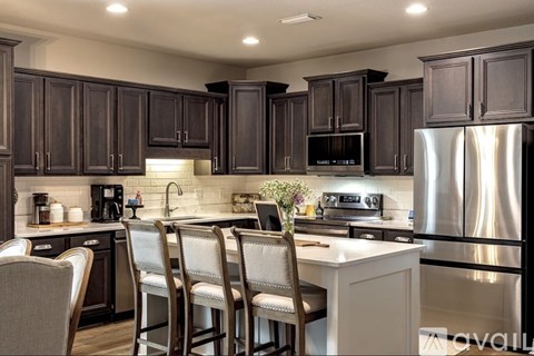 A kitchen with dark brown cabinets and a white countertop.