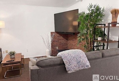A living room with a grey couch and a flat screen TV mounted above a fireplace.