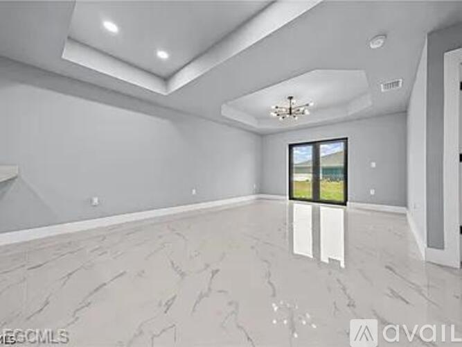 A spacious room with marble flooring and a chandelier.