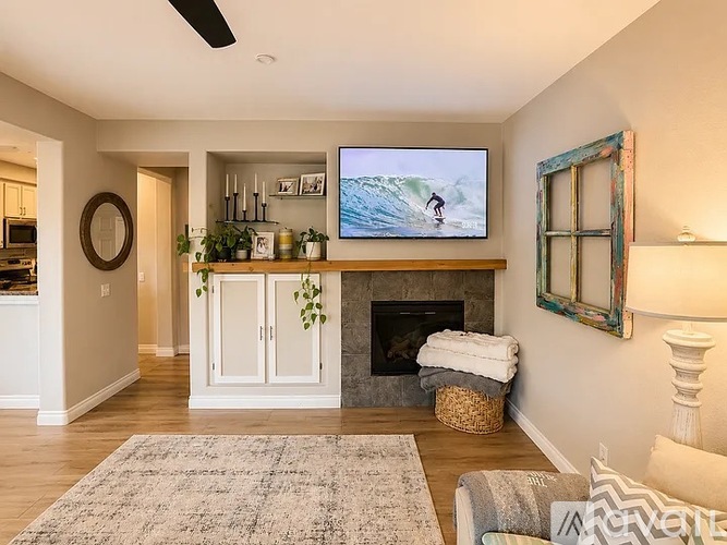 A living room with a fireplace and a television mounted above it.
