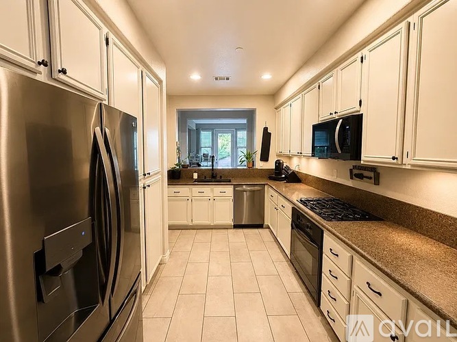 A kitchen with white cabinets and a stainless steel refrigerator.
