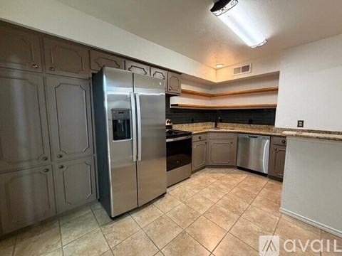 A kitchen with a stainless steel refrigerator and a tiled floor.