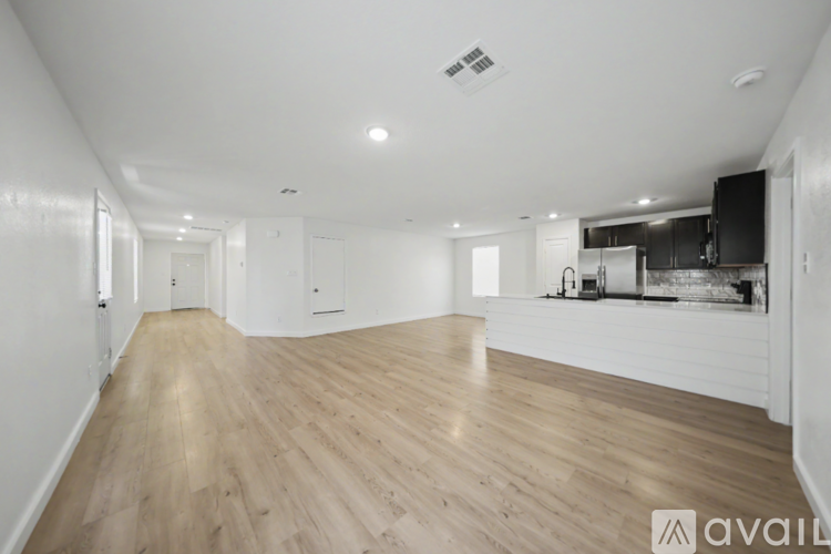 A spacious room with wooden flooring and white walls.